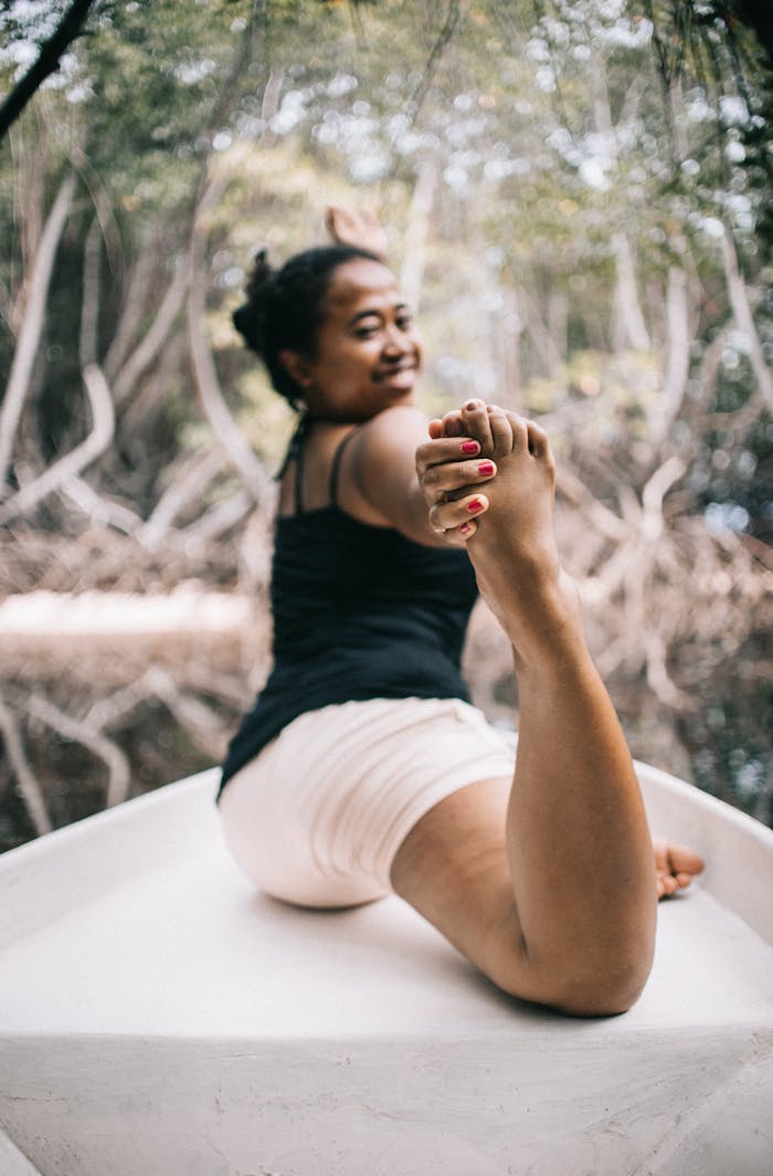 A woman exercises outdoors on a boat, showcasing flexibility in a peaceful natural setting.