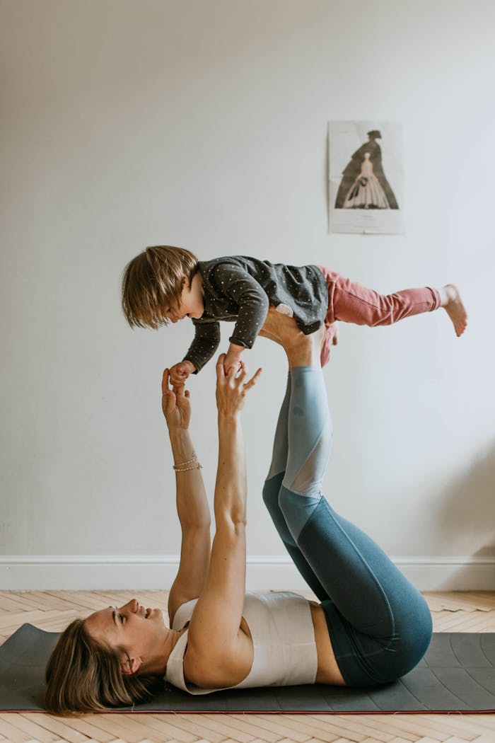services-04 A mother and daughter bonding through acro yoga at home, showcasing strength, balance, and togetherness.